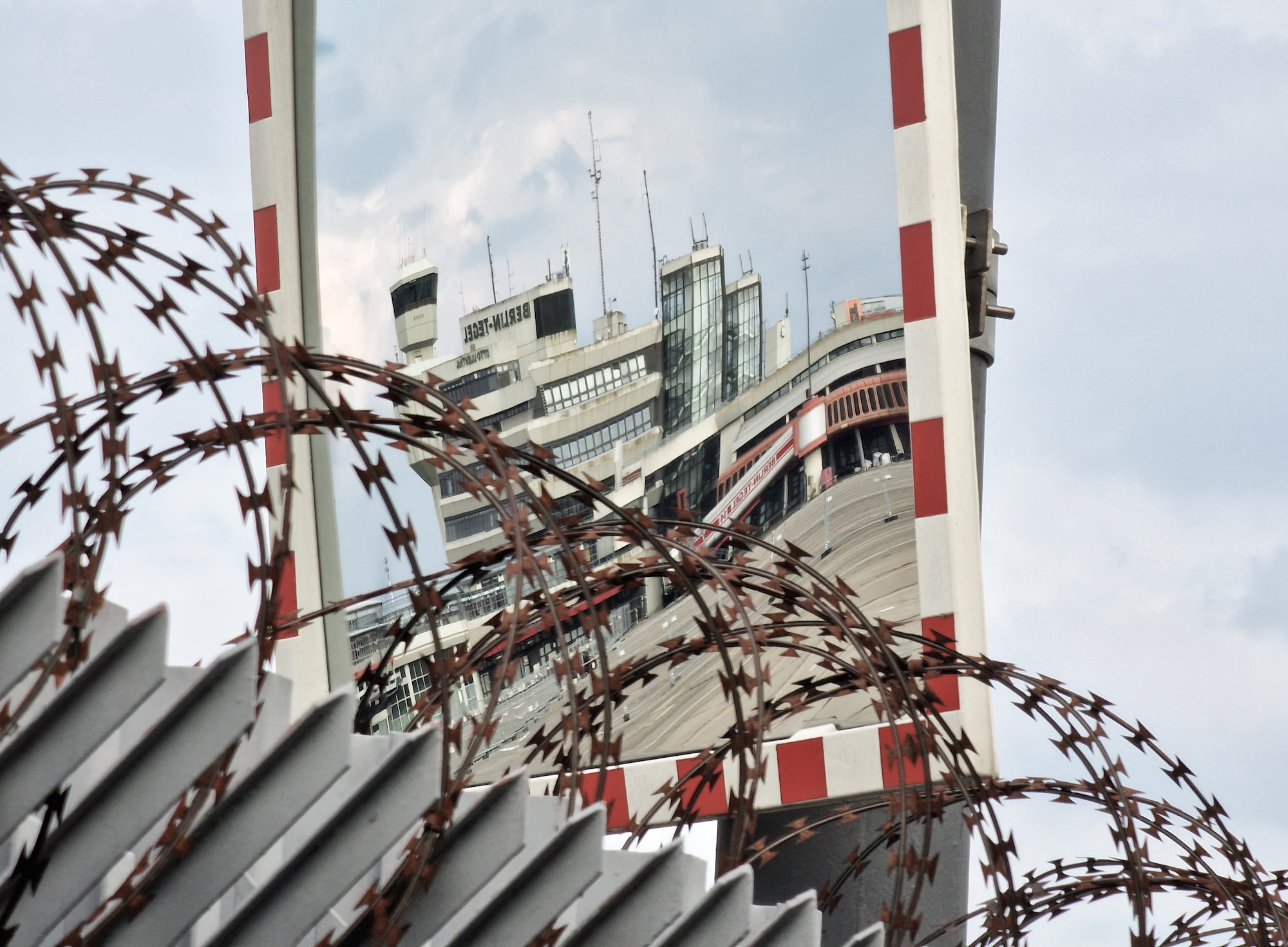 Gebäude des Flughafens im Spiegel hinter Stacheldraht