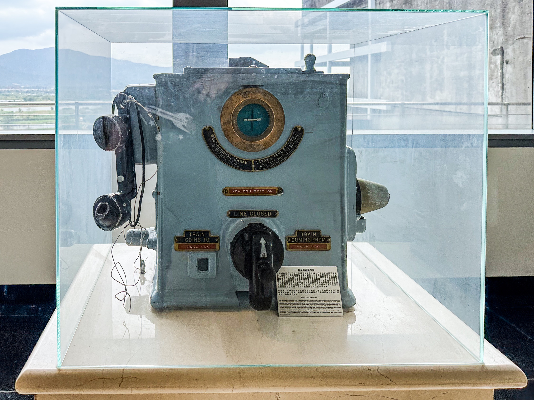 Ein altes Gerät in einer Vitrine. Es sieht aus wie ein sehr großes altes Telefon. In der Mitte ein Dreschalter, den man zwischne den beiden Richtungen umschalten kann.