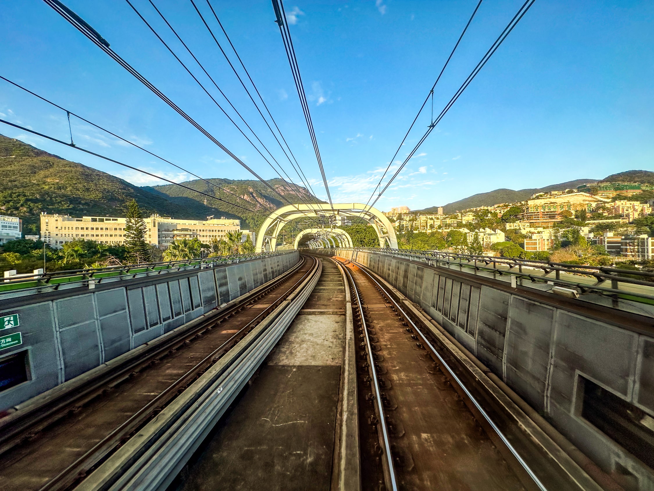 Blick aus dem Fenster entlang der Strecke. Es sind steile, bebaute Berge zu sehen.