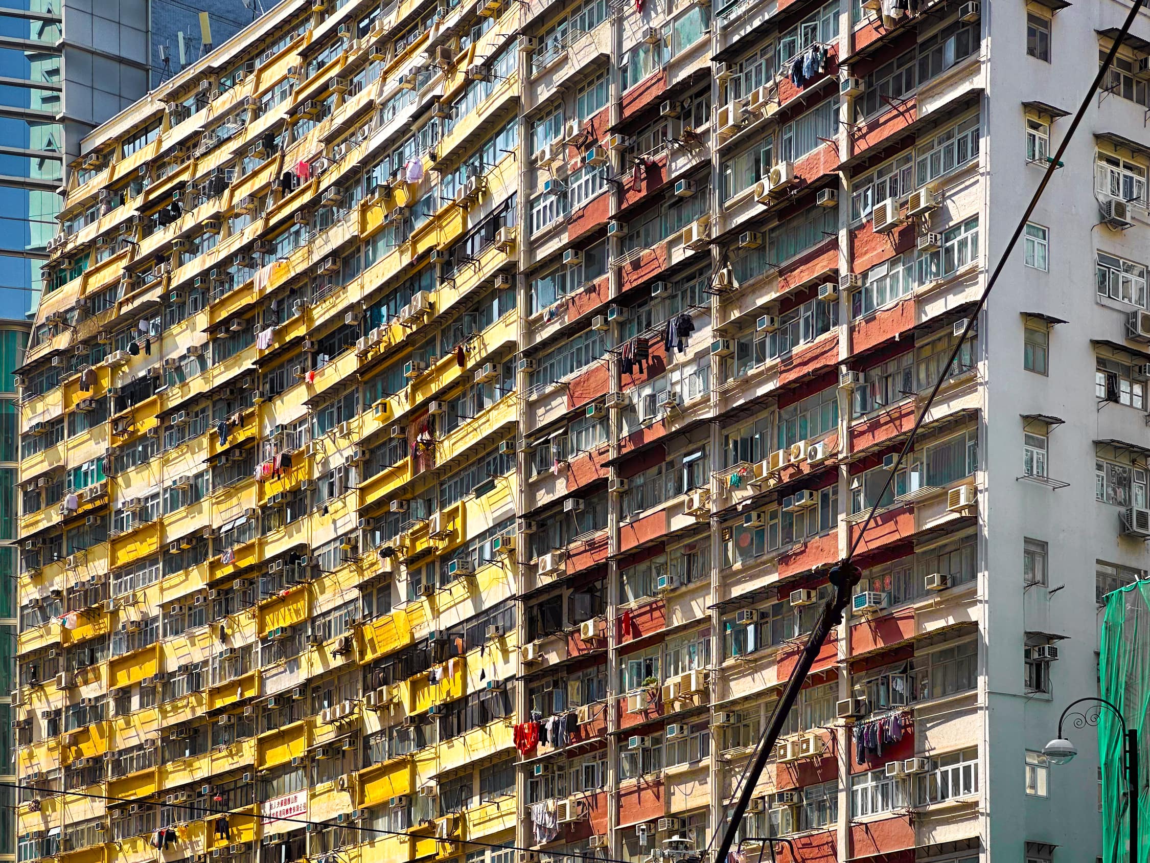 In einer Kurve Angeordnete Wohnhochhäuser. Aus vielen Fenstern hängt Wäsche. Ein teil des Stromabnehmers der vorherfahrenden Tram und die Oberleitung kreuzen das Bild