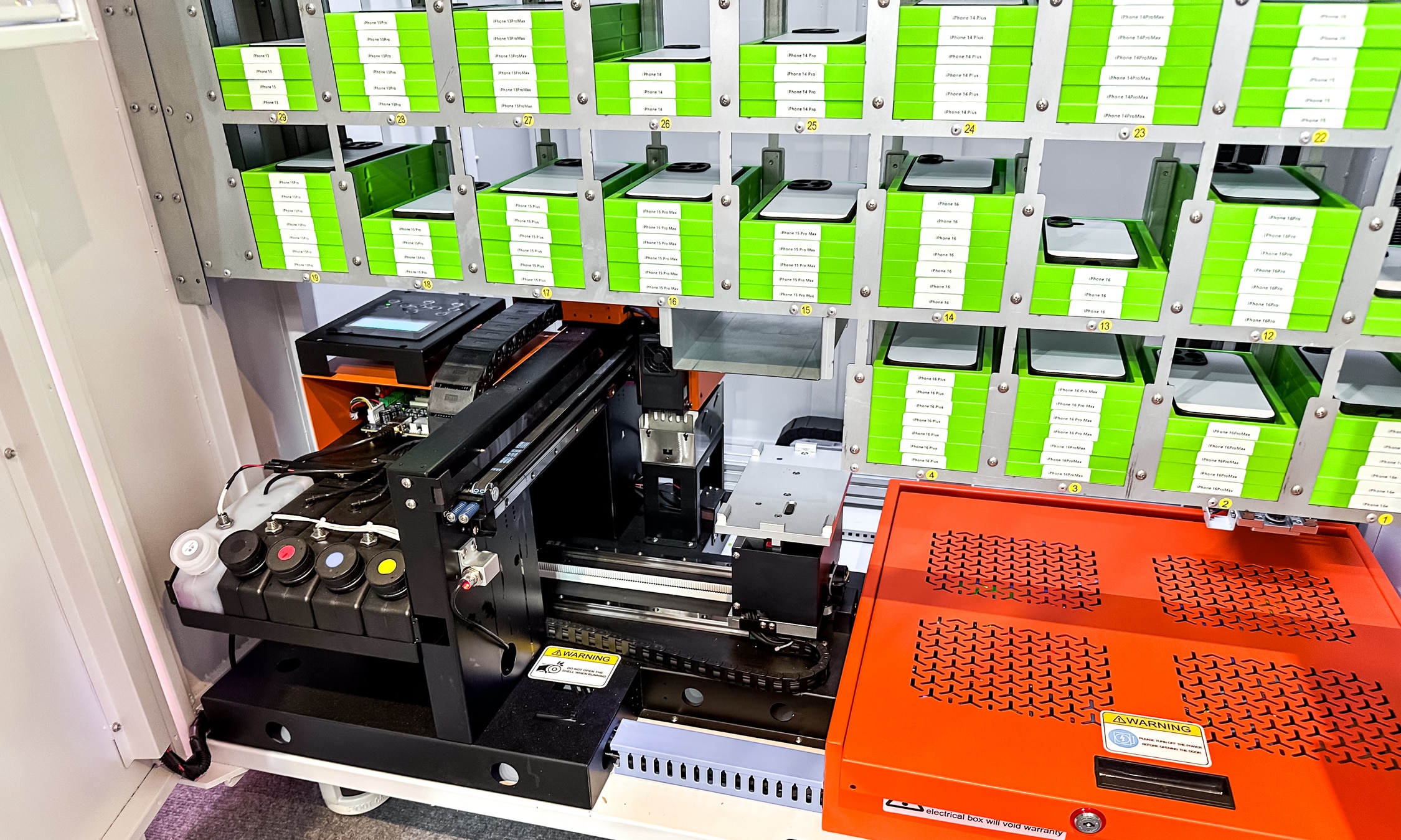 Blick in einen Automaten der Handyhüllen bedruckt. Oben ist ein Regal in dem die Hüllen in Halterungen aus Plastik liegen und unten steht ein UV Printer