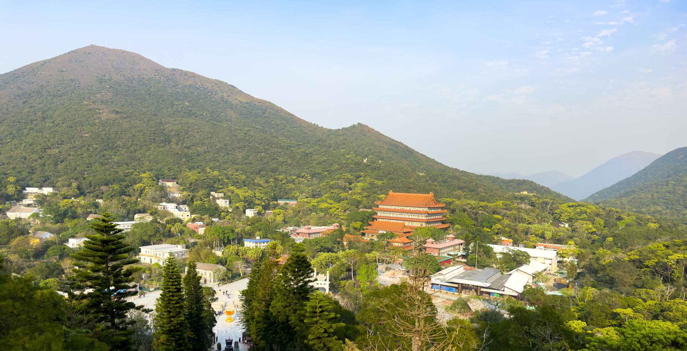 Blick in ein Tal. Im Tal am Fuße eines weiteren Berges ein großes Kloster, im Baustil eines chinesischen Tempels